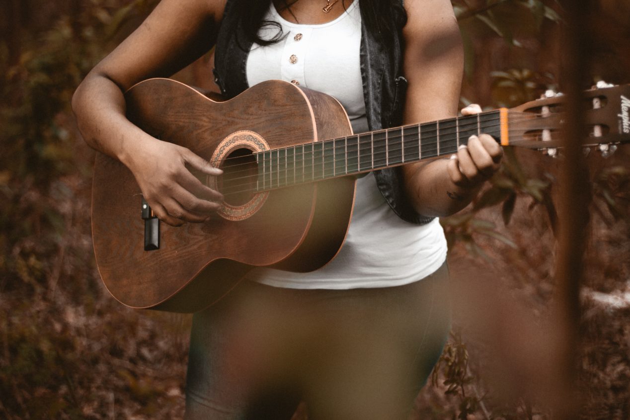 Photo of a woman playing guitar outside.