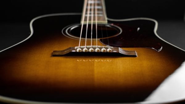 Photo of a sunburst acoustic guitar looking up from the bridge.