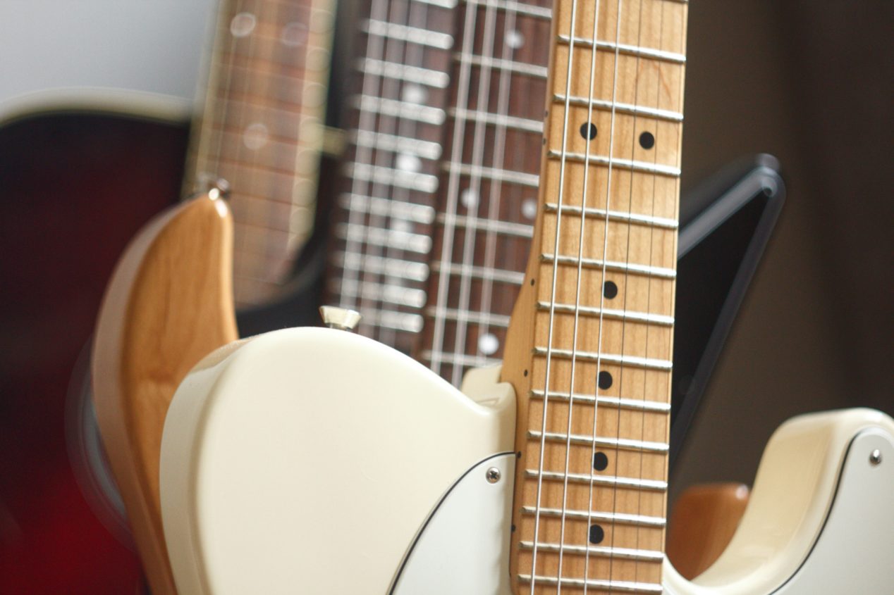Close up photo of multiple guitars sitting upright. 