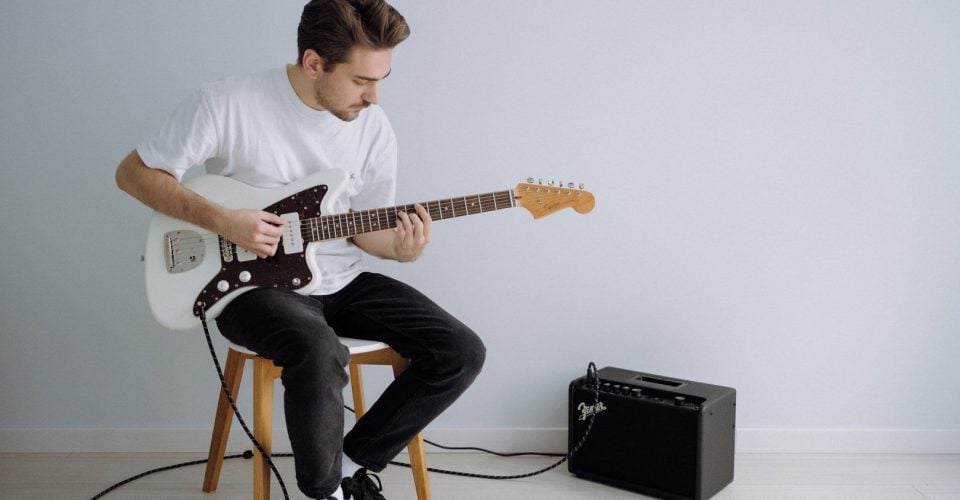 Photo of a man playing a Jazzmaster in a white room.