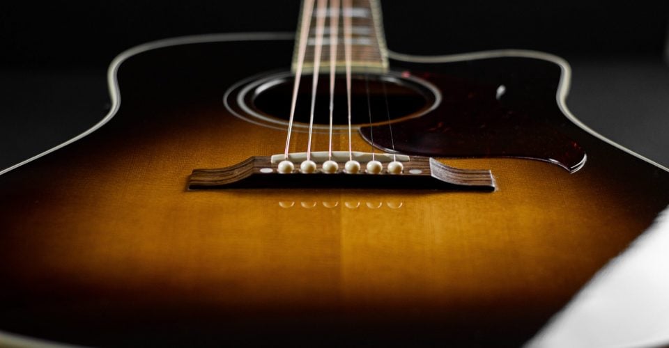 Photo of a sunburst acoustic guitar looking up from the bridge.